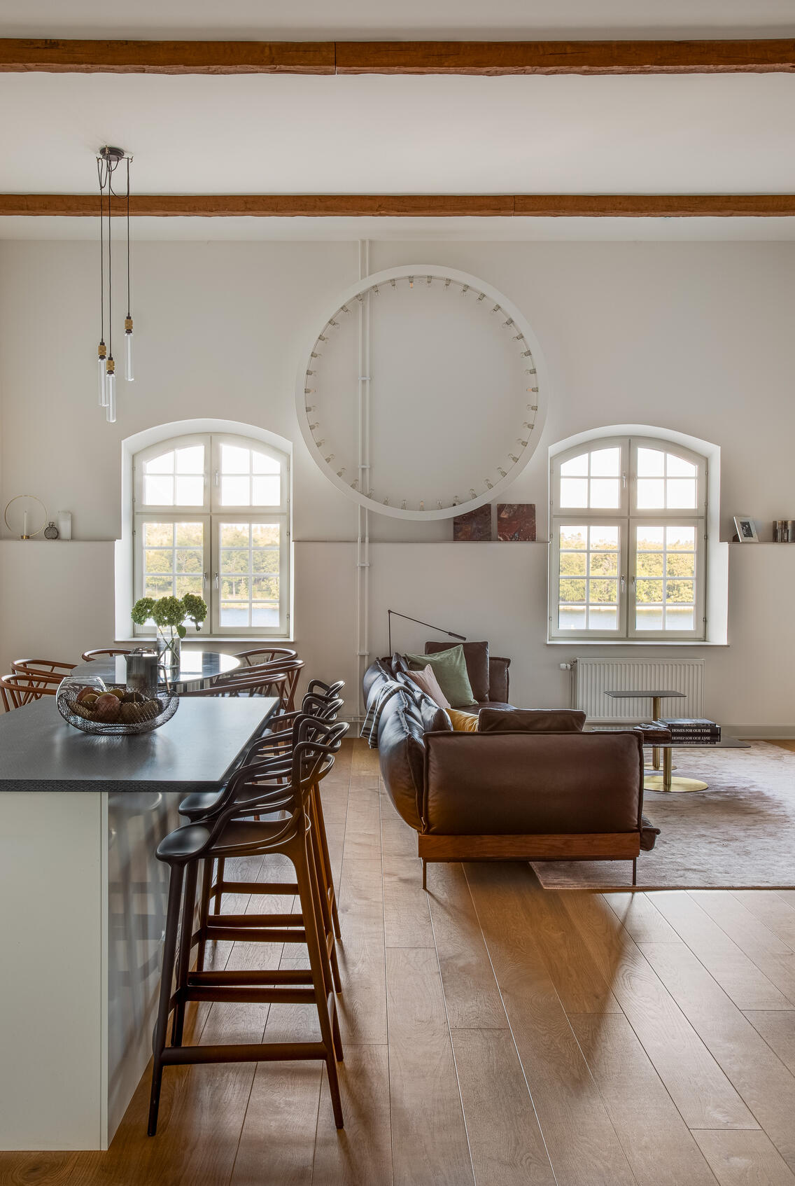 Open-plan loft apartment with arched windows, exposed beams and a leather sofa. Open-plan loft apartment with arched windows, exposed beams and a leather sofa.